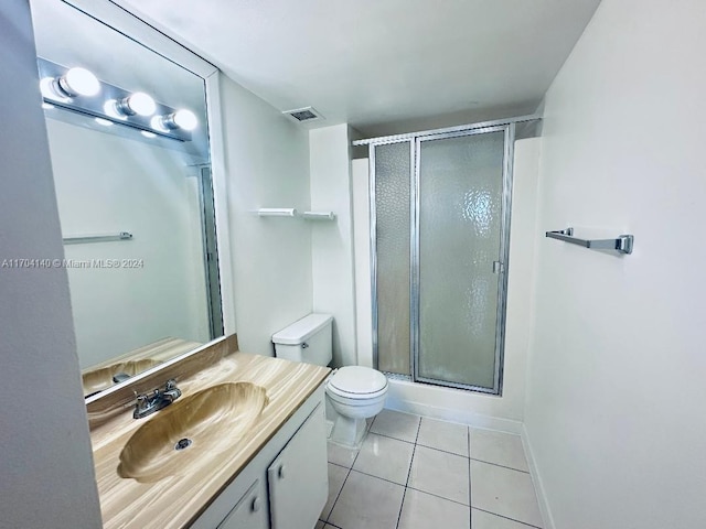 bathroom featuring tile patterned flooring, vanity, toilet, and a shower with door