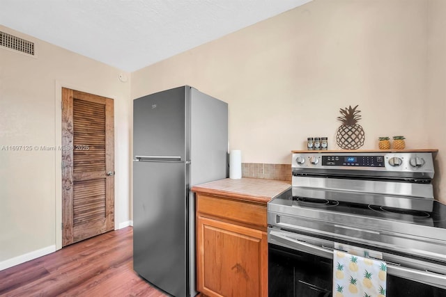 kitchen featuring stainless steel appliances, tile countertops, wood-type flooring, and a textured ceiling