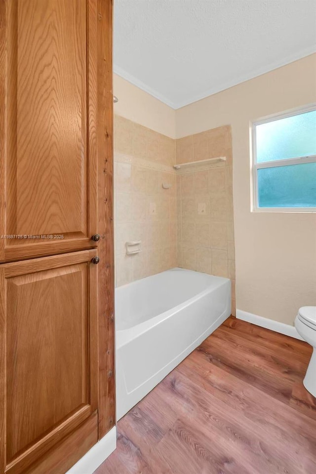 bathroom with shower / bathing tub combination, hardwood / wood-style floors, and toilet