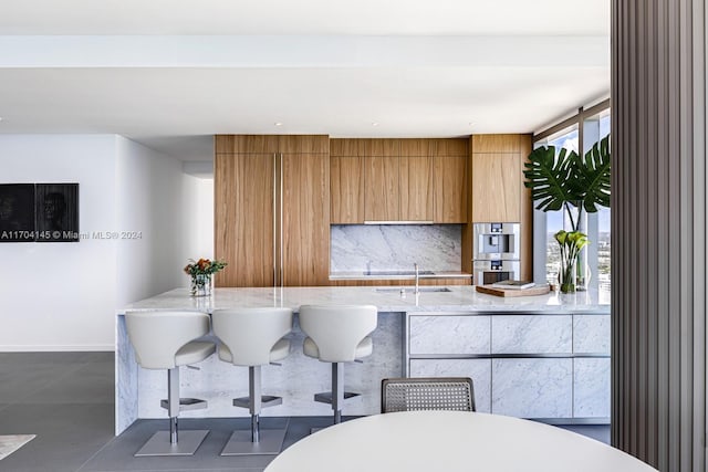 kitchen with a breakfast bar, stainless steel double oven, and sink