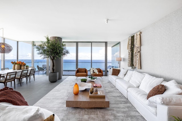 living room with concrete flooring, a water view, plenty of natural light, and a wall of windows