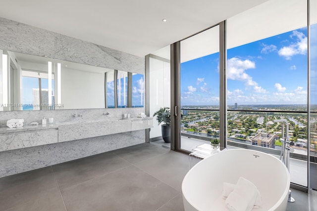 interior space with vanity, concrete floors, a wall of windows, and a tub