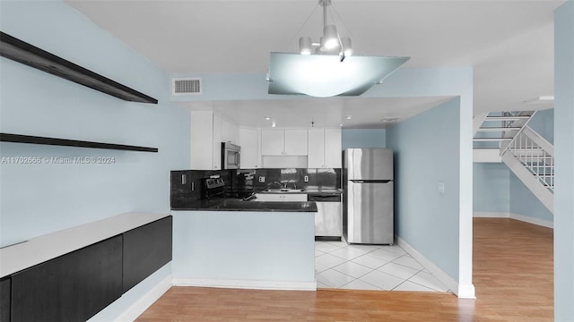 kitchen featuring pendant lighting, light wood-type flooring, white cabinetry, and stainless steel appliances