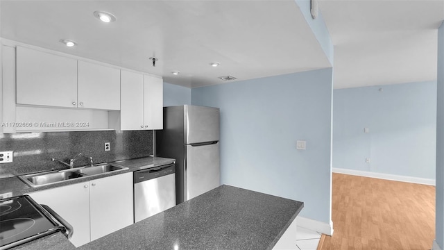 kitchen with appliances with stainless steel finishes, backsplash, sink, light hardwood / wood-style flooring, and white cabinets