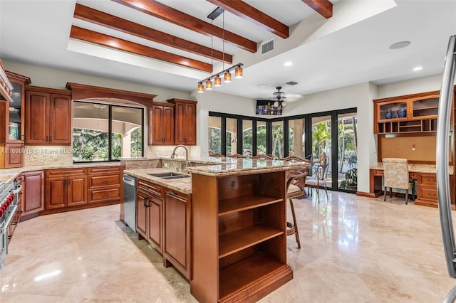 kitchen featuring a wealth of natural light, sink, an island with sink, and stainless steel dishwasher