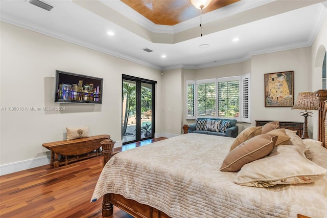 bedroom featuring french doors, a tray ceiling, wood-type flooring, access to outside, and ornamental molding