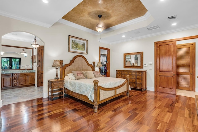 bedroom with connected bathroom, hardwood / wood-style flooring, ceiling fan, and ornamental molding