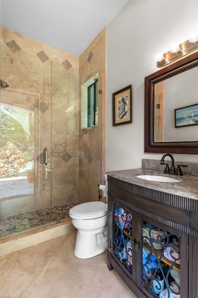 bathroom with an enclosed shower, vanity, toilet, and tile patterned flooring