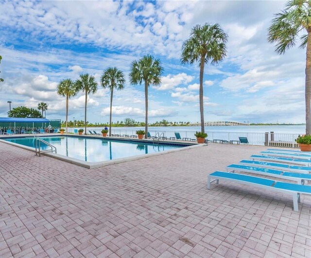 view of pool featuring a water view and a patio