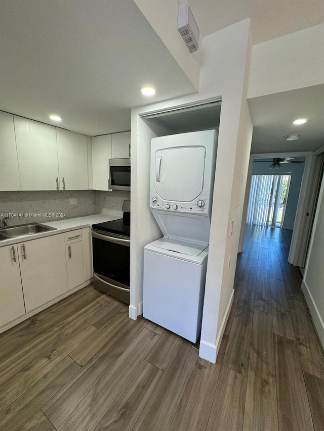 clothes washing area with ceiling fan, sink, dark hardwood / wood-style floors, and stacked washer / drying machine