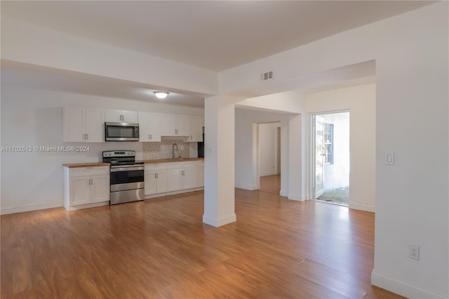 kitchen featuring decorative backsplash, appliances with stainless steel finishes, light wood-type flooring, sink, and white cabinetry