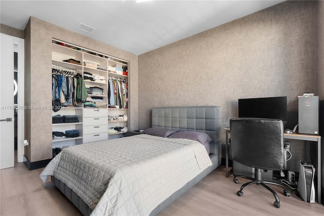 bedroom with light hardwood / wood-style floors and a closet