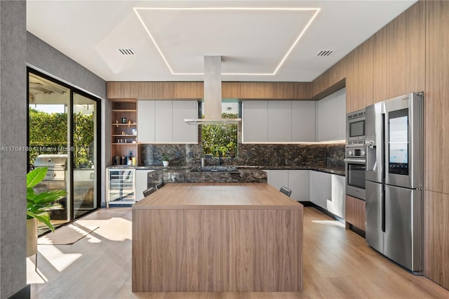 kitchen with white cabinetry, light hardwood / wood-style flooring, beverage cooler, and stainless steel appliances