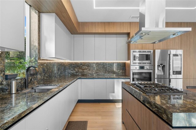 kitchen featuring white cabinets, sink, island exhaust hood, and appliances with stainless steel finishes