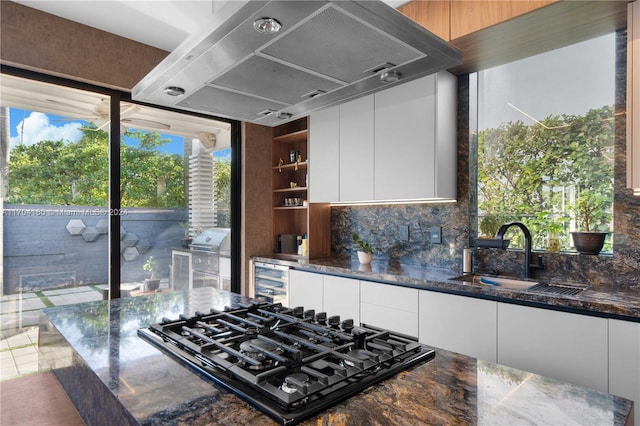 kitchen with white cabinetry, black gas stovetop, dark stone countertops, and sink