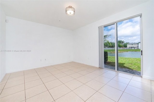 tiled spare room featuring a water view