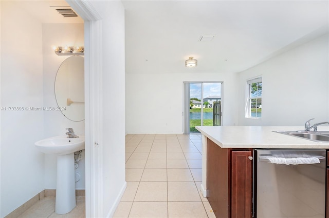 kitchen with stainless steel dishwasher, light tile patterned floors, and sink