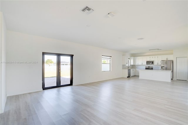 unfurnished living room featuring french doors and light hardwood / wood-style flooring