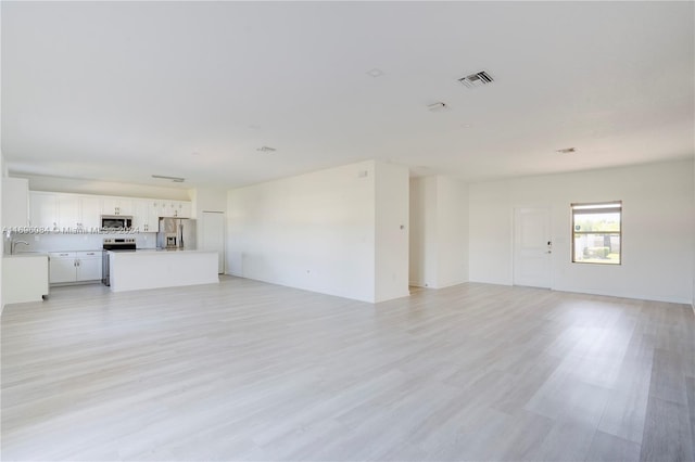 unfurnished living room featuring light wood-type flooring and sink