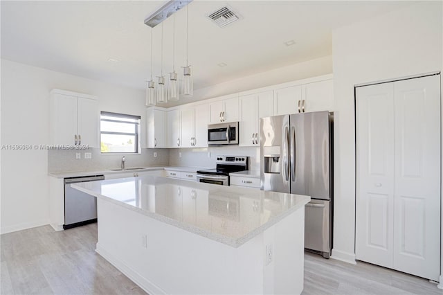 kitchen with appliances with stainless steel finishes, white cabinets, a center island, light hardwood / wood-style floors, and hanging light fixtures