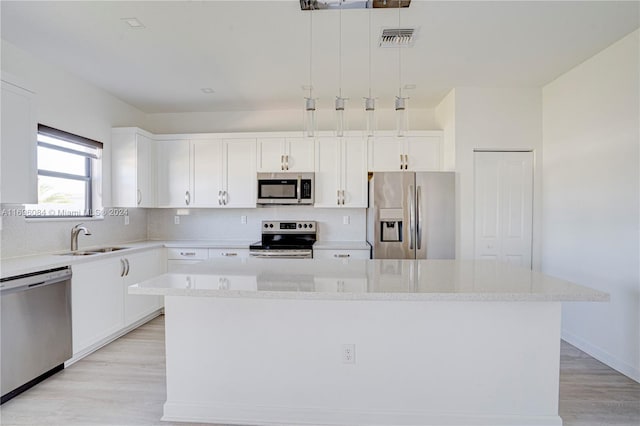 kitchen featuring sink, appliances with stainless steel finishes, decorative light fixtures, a kitchen island, and white cabinetry