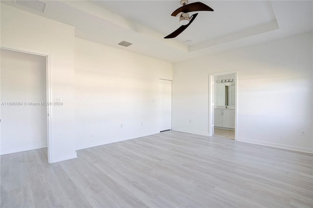 empty room featuring a tray ceiling, light hardwood / wood-style flooring, and ceiling fan