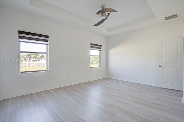 spare room with ceiling fan, a raised ceiling, and light hardwood / wood-style flooring