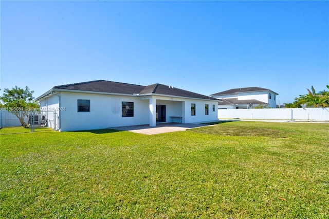 back of house featuring a lawn and a patio