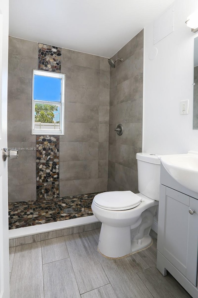 bathroom featuring toilet, vanity, and a tile shower