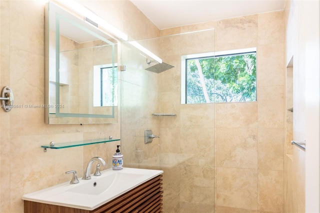 bathroom with a tile shower, vanity, and tile walls