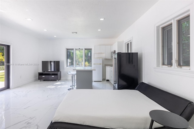 bedroom featuring stainless steel fridge, white refrigerator, access to outside, and a textured ceiling