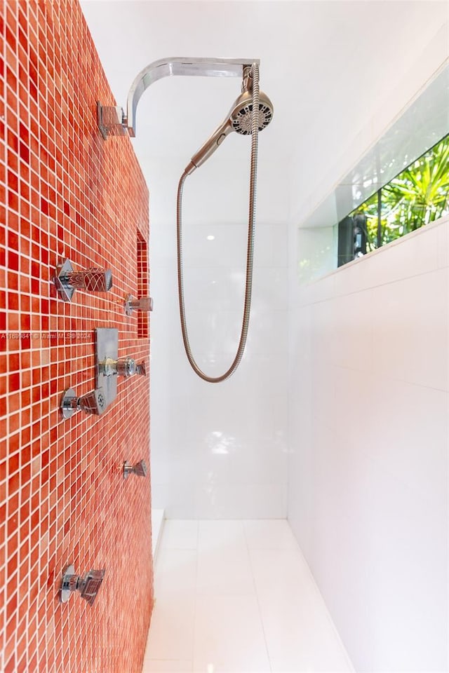 bathroom with a tile shower and tile patterned flooring