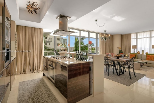 kitchen with decorative light fixtures, stainless steel gas cooktop, island exhaust hood, light tile patterned floors, and a chandelier