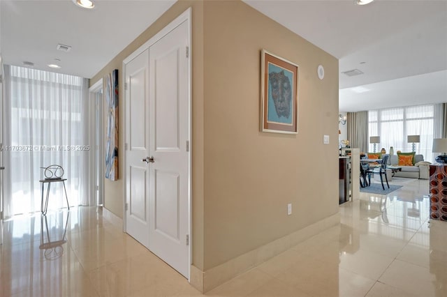 corridor with light tile patterned floors, recessed lighting, visible vents, baseboards, and expansive windows