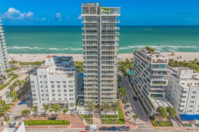 drone / aerial view featuring a water view, a beach view, and a city view