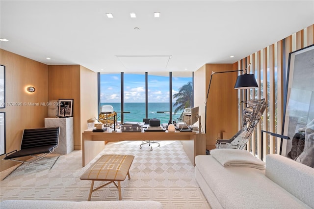 interior space featuring expansive windows, light carpet, a water view, and wood walls