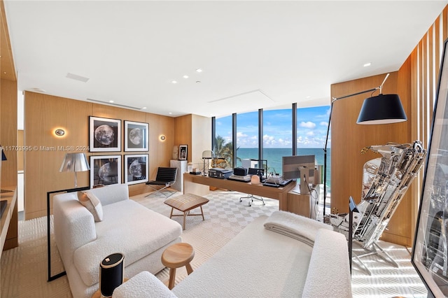 living room with floor to ceiling windows, a water view, and wooden walls