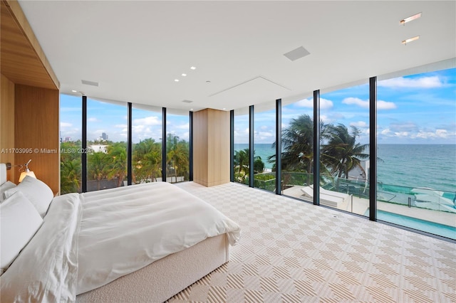 unfurnished bedroom with access to exterior, a water view, and a wall of windows