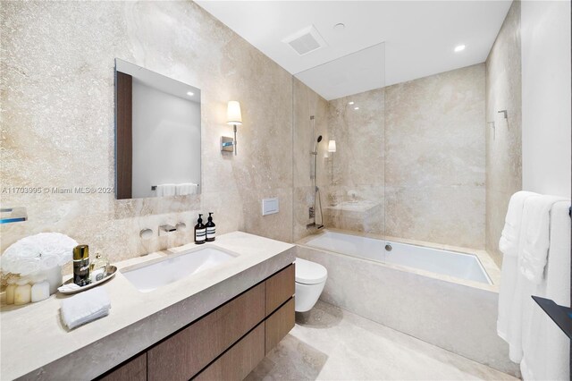 full bathroom with tiled shower / bath combo, toilet, tile walls, and vanity