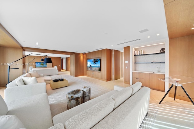 living room featuring built in shelves, wood walls, and sink