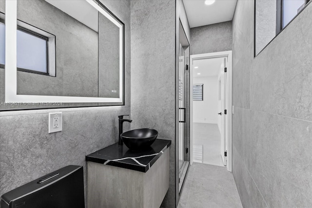 bathroom featuring concrete flooring, vanity, and tile walls