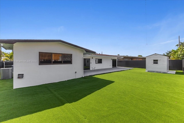 back of house featuring a lawn, a patio area, a storage shed, and central AC