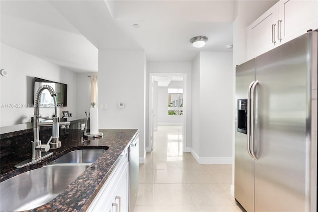 kitchen with white cabinets, stainless steel appliances, dark stone counters, and sink