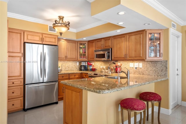 kitchen with a kitchen breakfast bar, sink, ornamental molding, appliances with stainless steel finishes, and light stone counters