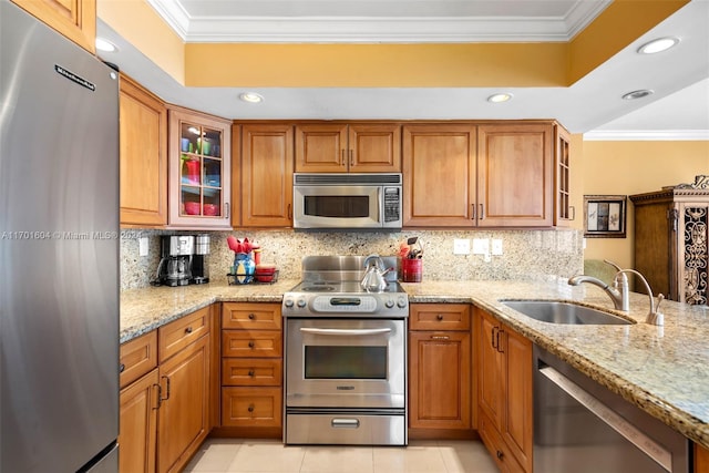 kitchen featuring light stone countertops, appliances with stainless steel finishes, ornamental molding, and sink