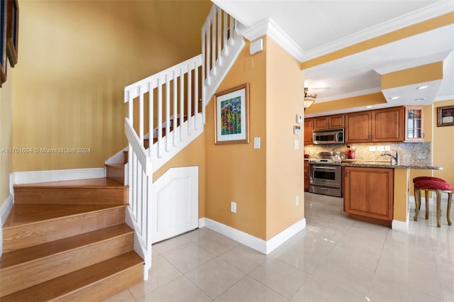 stairs with tile patterned floors, ornamental molding, and sink