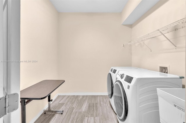 clothes washing area featuring washing machine and dryer, sink, and light hardwood / wood-style floors