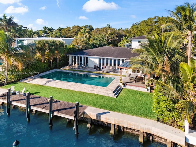 view of pool featuring a lawn, a water view, and a patio