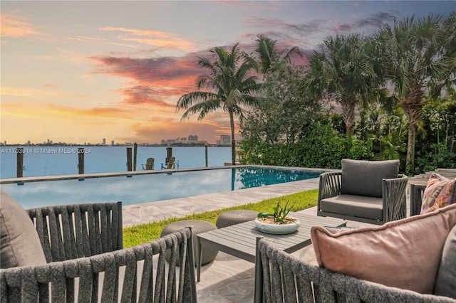 pool at dusk featuring a water view