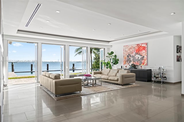 living room with a tray ceiling and a water view